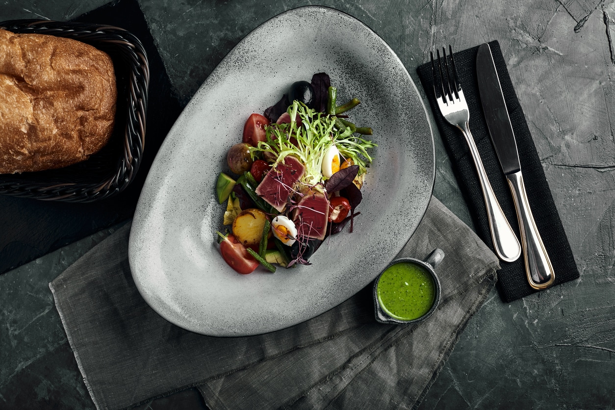 Membership Vegetable salad with fresh tuna and avocado citrus in a gray plate on a gray slate, stone or concrete background. Top view with copy space